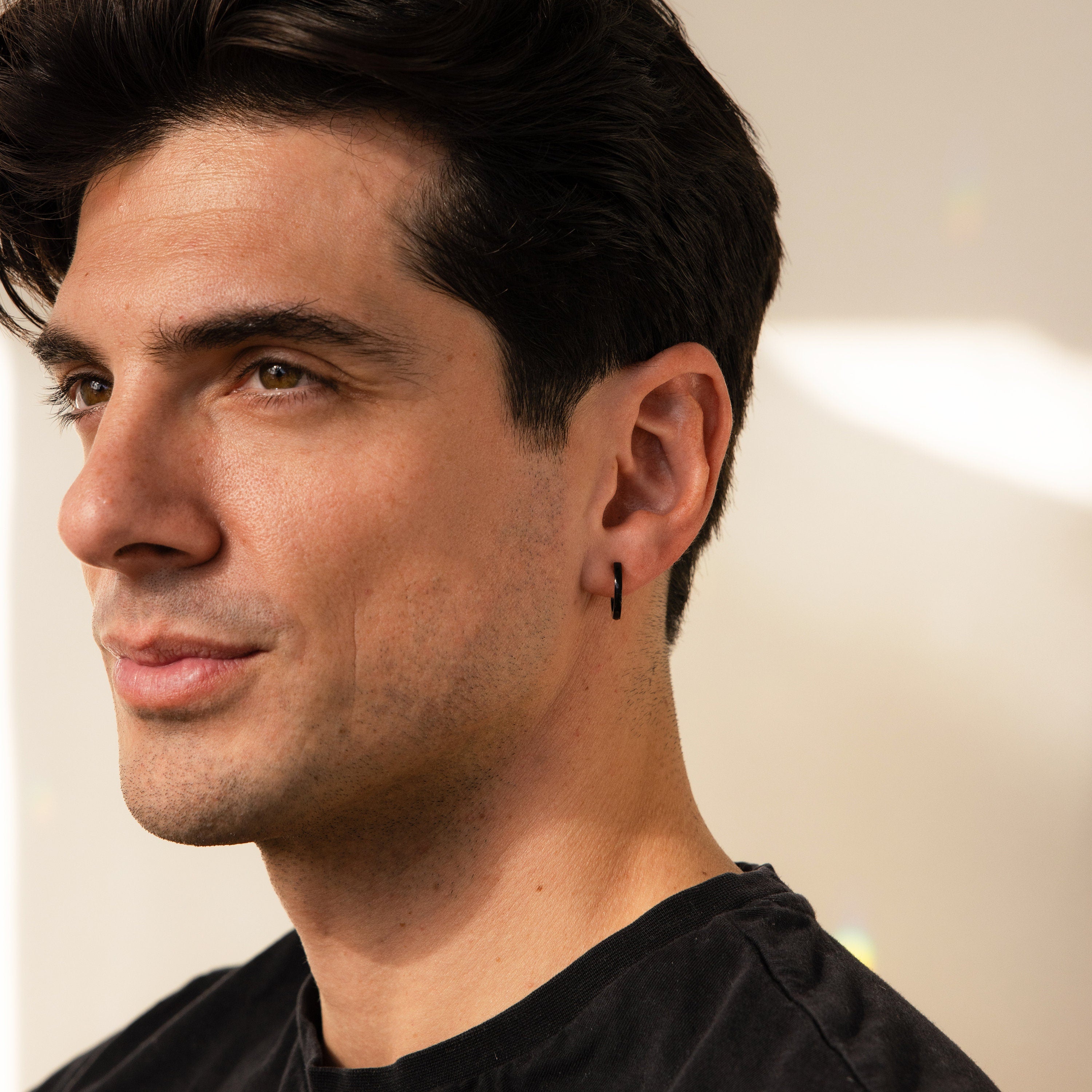 Man with short dark hair wearing a black shirt and the Men's Black Hoops Set, looking to the left.