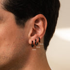 A close-up of a person's ear shows the Men's Black Hoops Set in 6mm, 9mm, and 11mm sizes—stylish earrings that make an ideal gift for him.