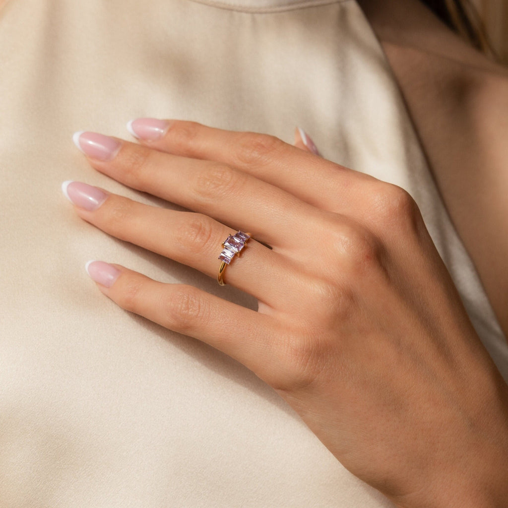 A hand adorned with the Art Deco Birthstone Ring, showcasing a sparkling baguette-cut stone.