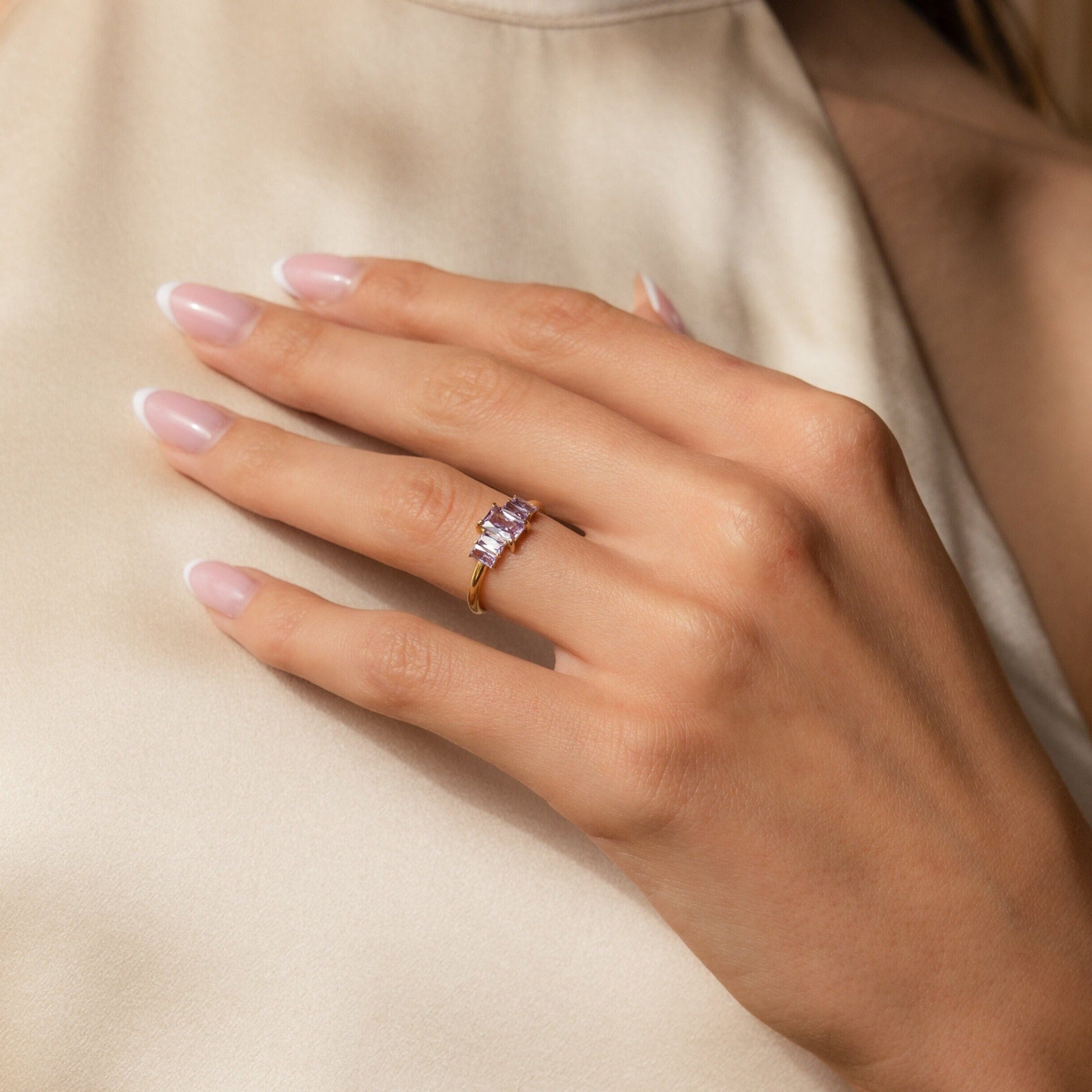 A hand adorned with the Art Deco Birthstone Ring, showcasing a sparkling baguette-cut stone.