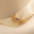 The Amethyst Stacking Ring Set features gold rings with purple gemstones on a cream satin ribbon, adding a bold, elegant touch to your style. This fashion-forward jewelry is perfect for stacking and making a statement.