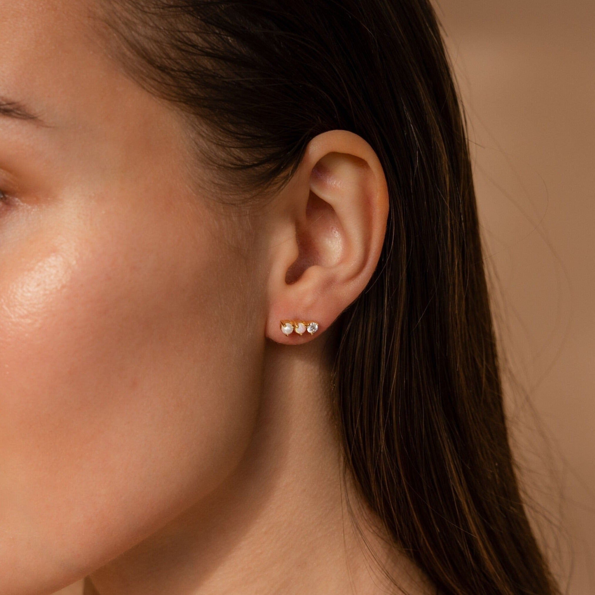 Close-up of a woman's ear wearing the Pearl, Opal & Diamond Studs—small gold and diamond earrings perfect for pairing with opal studs.