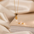 The Knot Pearl Necklace & Earrings Set displayed on a beige book with a soft, neutral fabric background—an elegant gift for her.