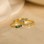 The Pave Triple Birthstone Ring features three gold bands with customizable green, blue, and yellow stones plus clear accents—an elegant personalized jewelry piece, perfect as a custom birthstone gift for any special occasion.