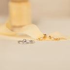 Two pairs of Marquise Inlay Huggies—one silver, one gold—are displayed on soft cream fabric.