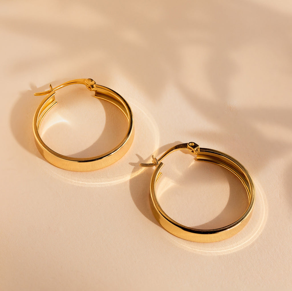 Thick Hoops rest on a light beige surface, casting soft shadows in the background for a modern touch.
