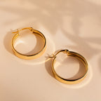 Thick Hoops rest on a light beige surface, casting soft shadows in the background for a modern touch.