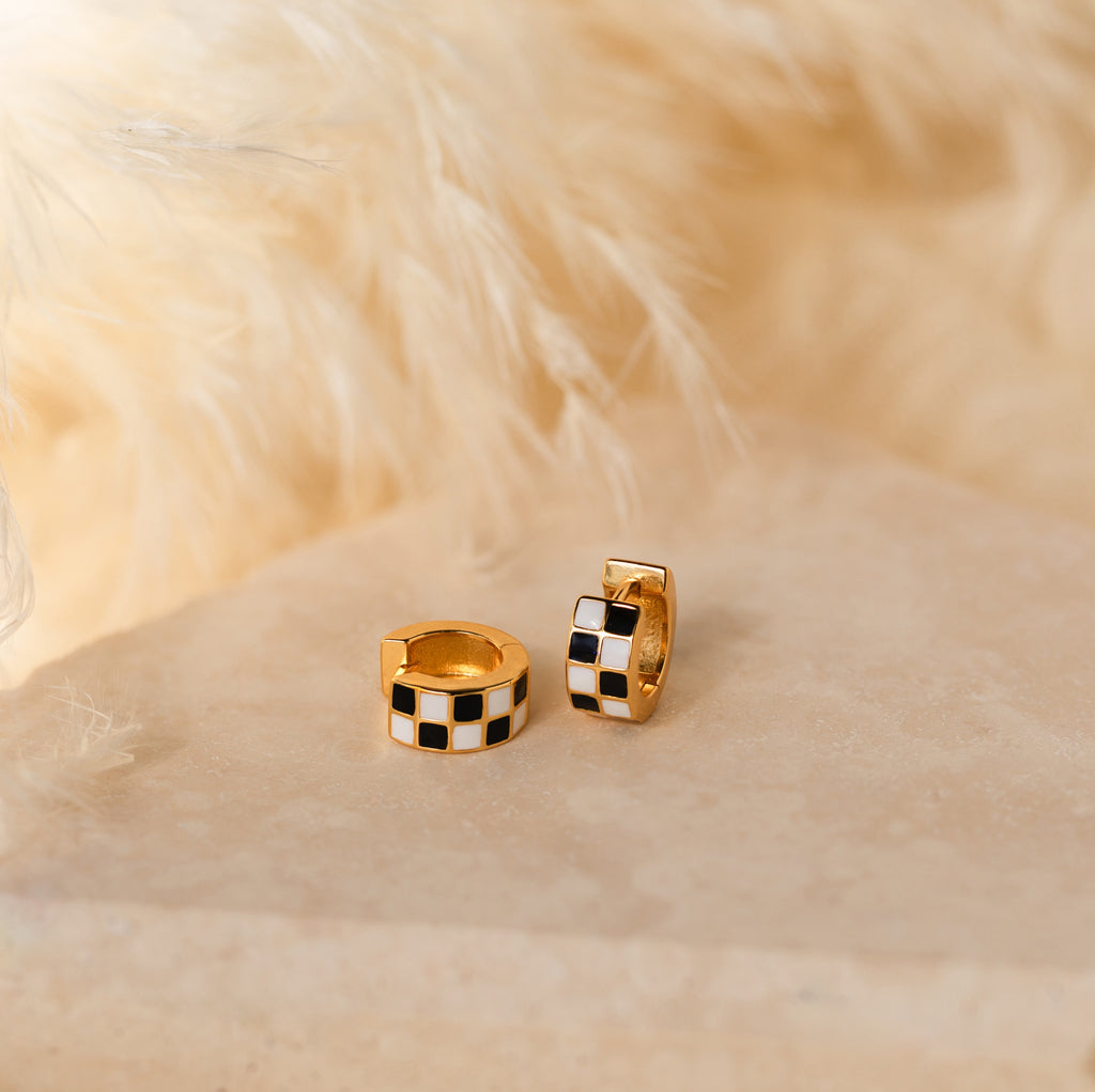Add a playful twist to your style with Checkered Huggies—chic hoop earrings featuring bold black and white checkered patterns.