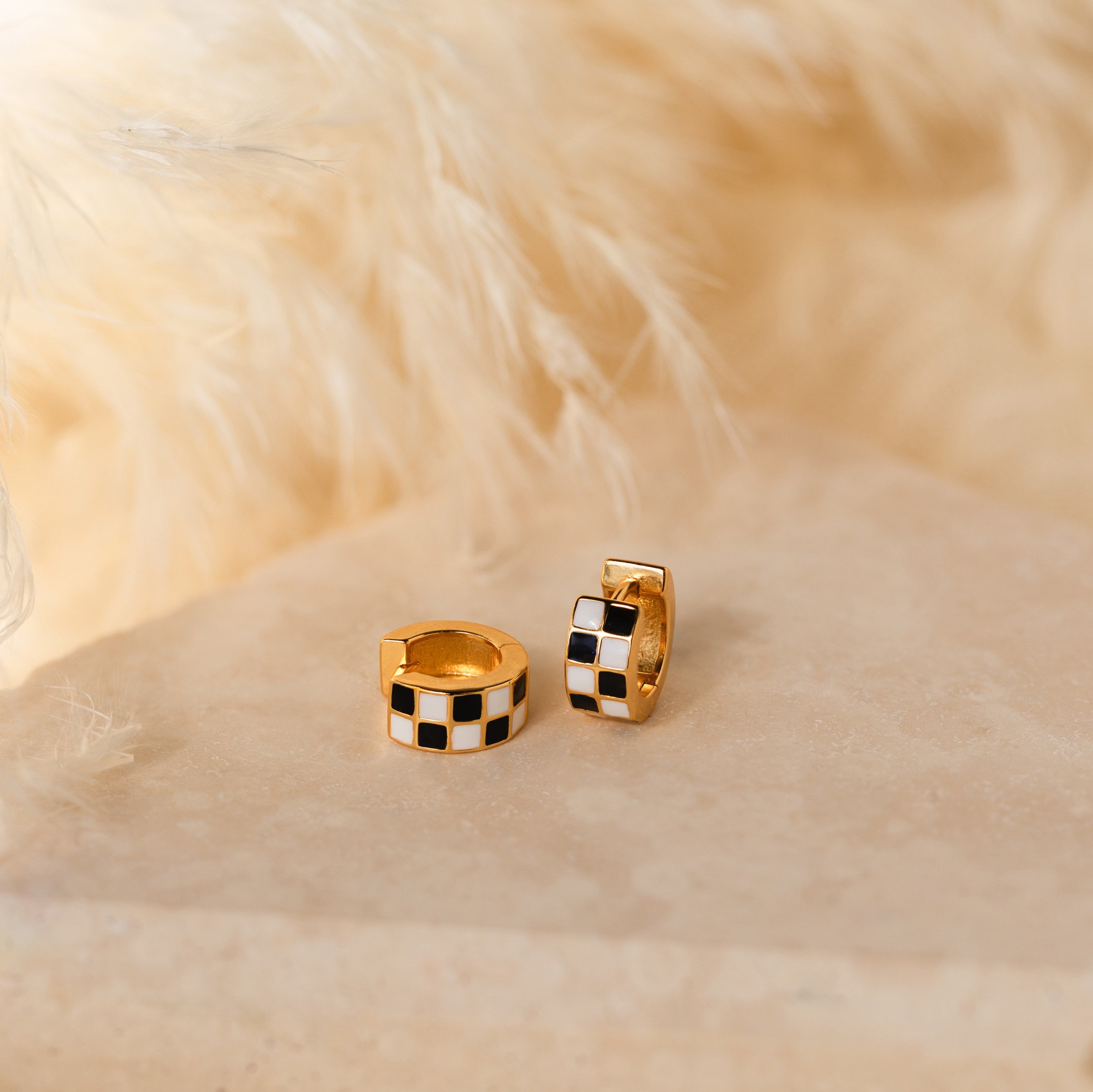 Add a playful twist to your style with Checkered Huggies—chic hoop earrings featuring bold black and white checkered patterns.