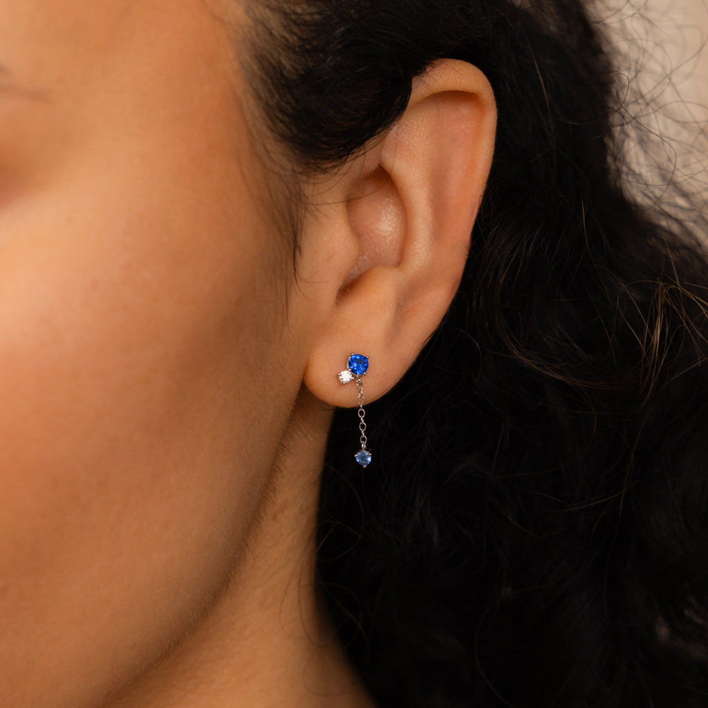 A close-up of a woman's ear wearing the Sapphire Diamond Drop Earrings, showcasing their elegant sapphire and diamond design.