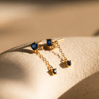 The Sapphire Diamond Drop Earrings feature gold drops with brilliant blue sapphires and sparkling diamond accents, adding a touch of timeless elegance.