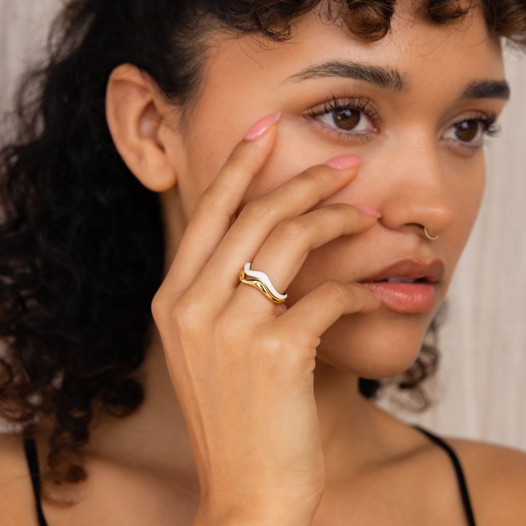 A woman with curly hair touches her face, highlighting the Duo Wave Ring Set on her finger—a stunning example of minimalist, uniquely designed rings.