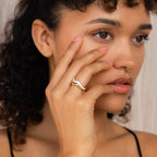 A woman with curly hair touches her face, highlighting the Duo Wave Ring Set on her finger—a stunning example of minimalist, uniquely designed rings.