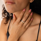 A woman with curly hair touches her neck, highlighting the Duo Wave Ring Set and her pink nail polish, while wearing a black strap top.