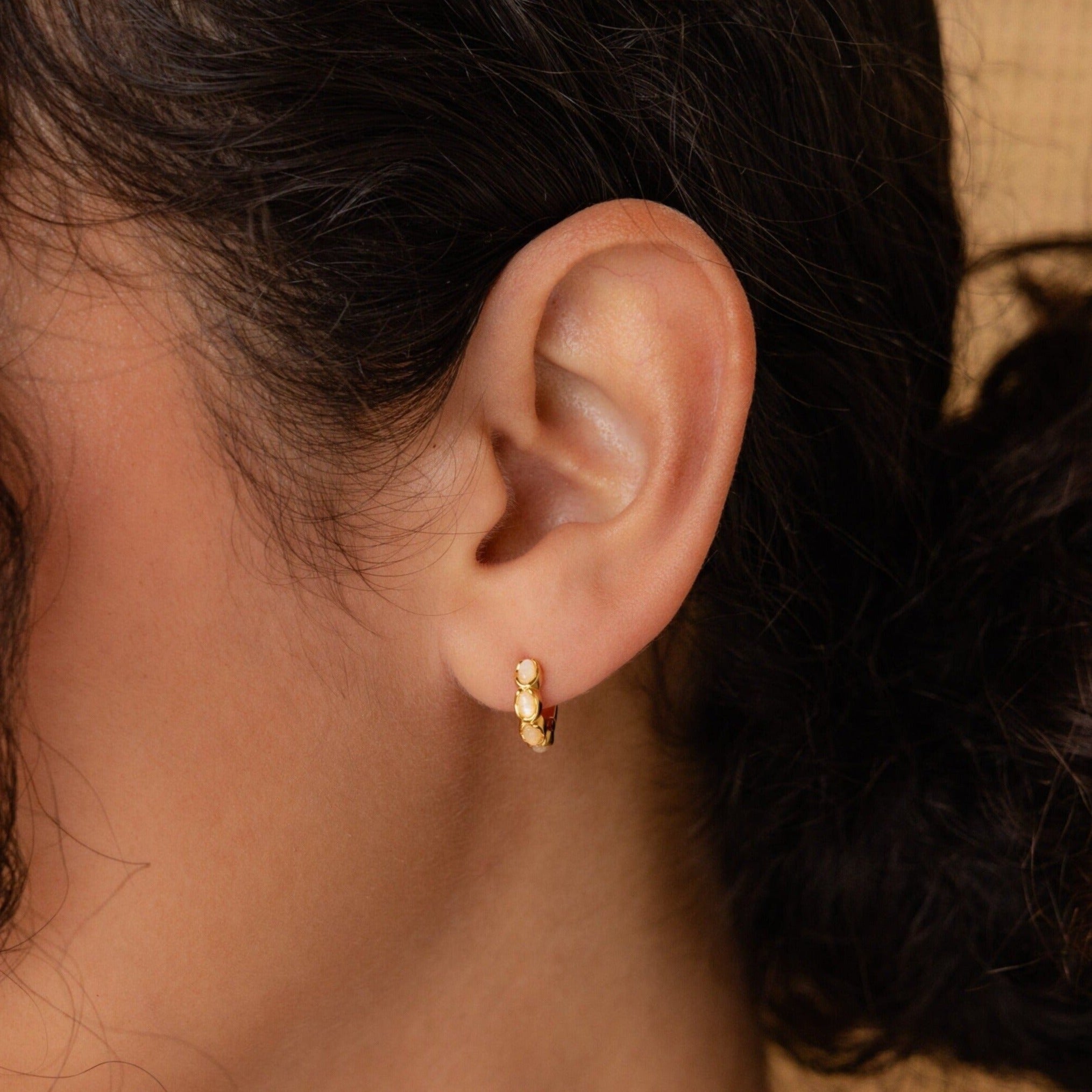 A close-up of a woman's ear adorned with Moonstone Huggies earrings.