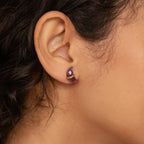 Close-up of model wearing a purple moon-shaped earring in gold. 