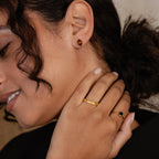 A woman with curly hair and nude nail polish smiles softly while wearing Herkimer Smoky Quartz Studs.