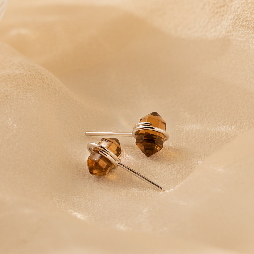 Herkimer Smoky Quartz Studs—elegant stud earrings featuring smoky quartz gemstone points set in silver, displayed on soft beige fabric for a subtle, earthy charm.
