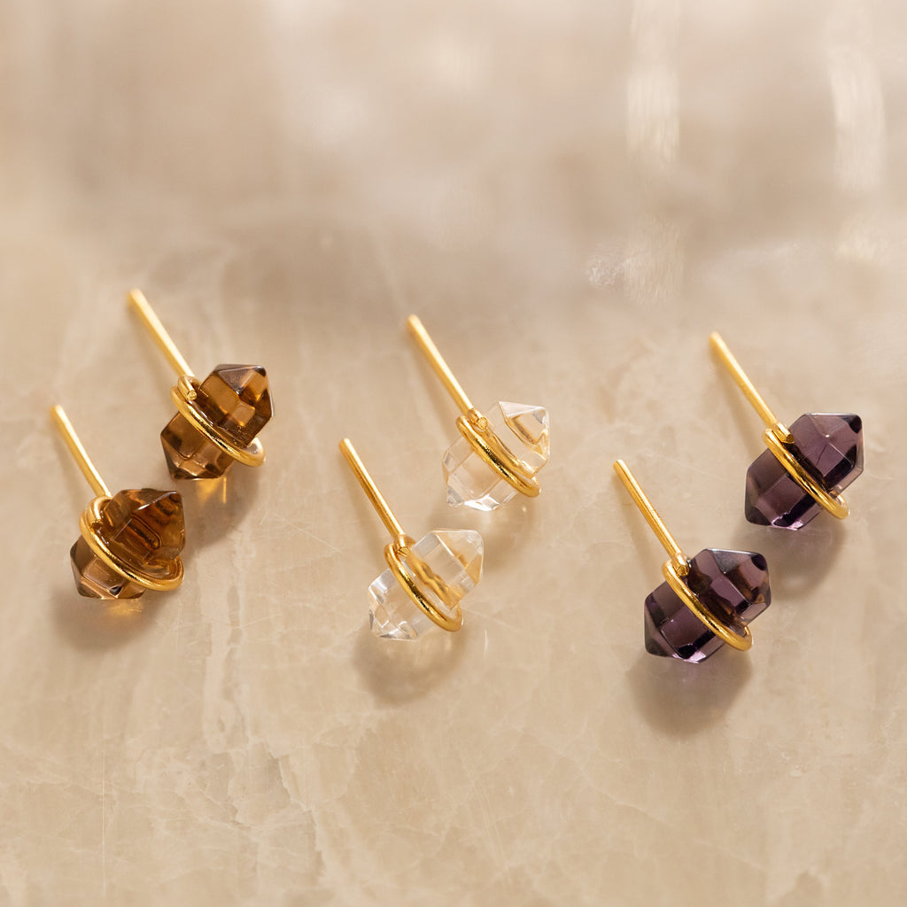 A collection of colorful earrings, featuring stunning quartz crystal pieces and eye-catching Herkimer Smoky Quartz Studs.