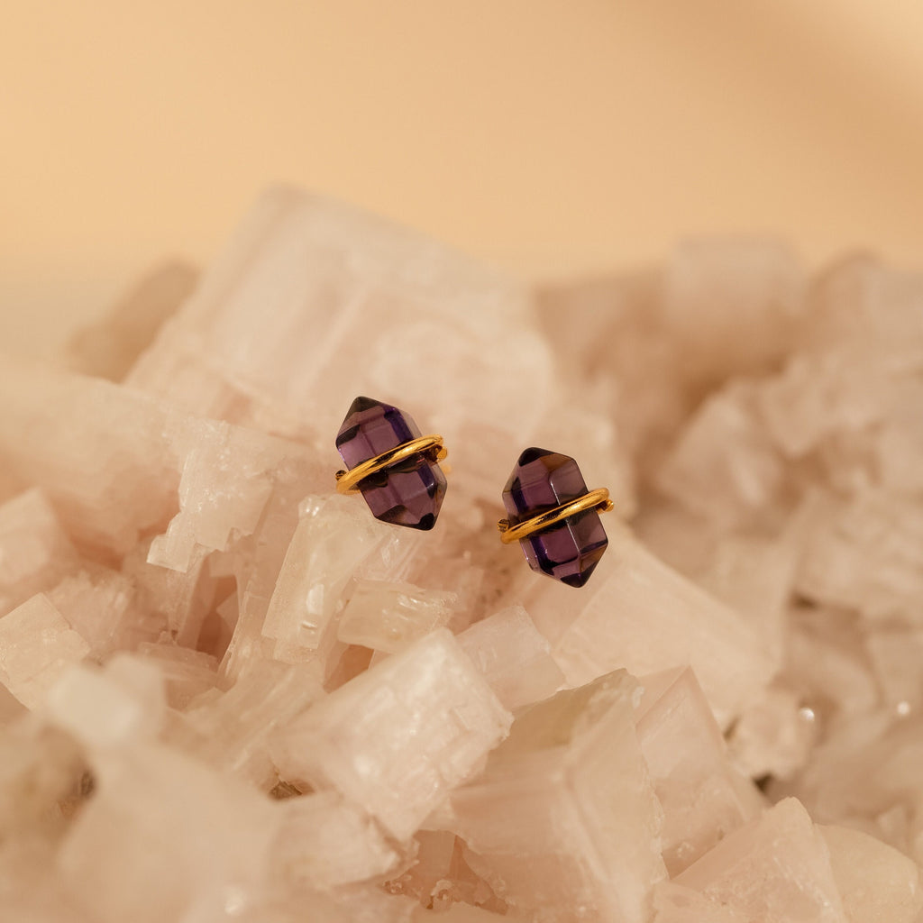 Amethyst Herkimer Studs displayed on a cluster of translucent crystals, highlighting their gold accents and captivating purple gemstone allure.