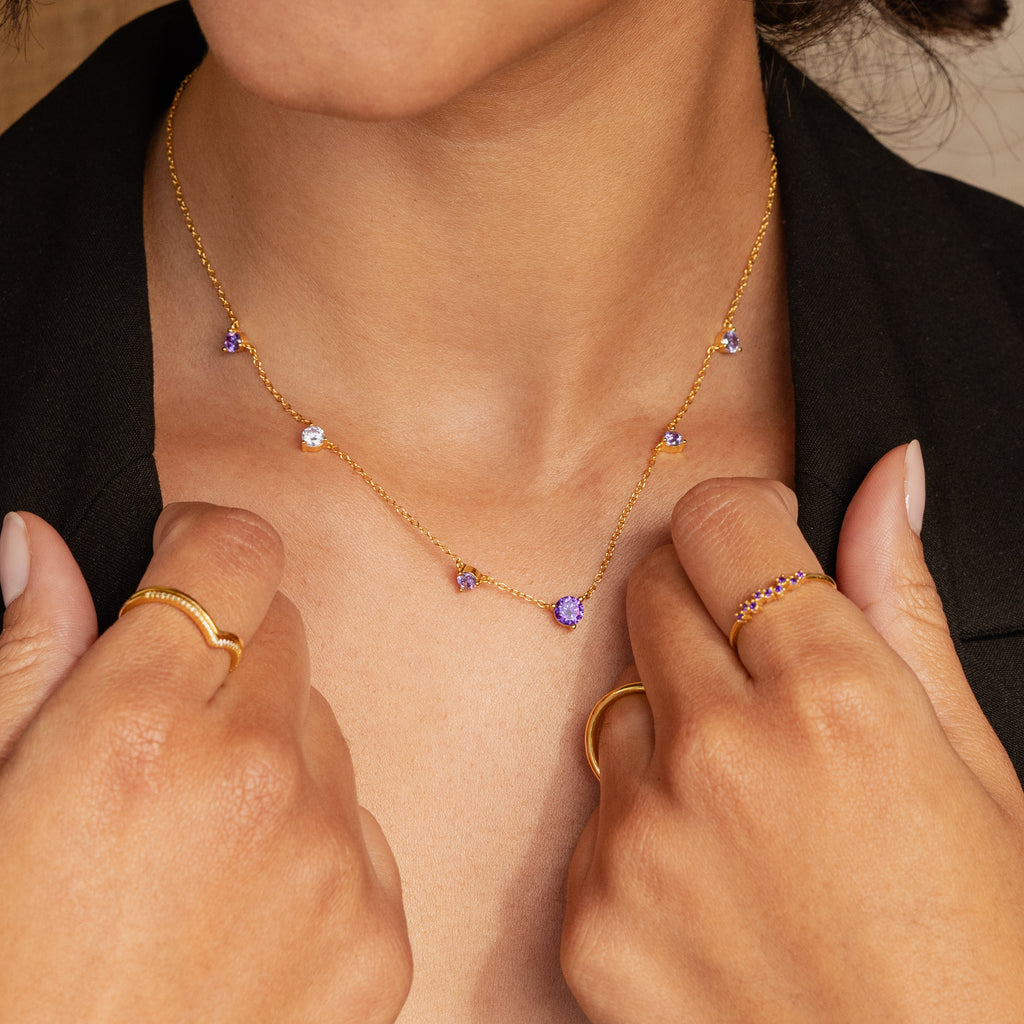 Amethyst Station Necklace featuring purple gemstone charms, paired with matching rings and a black top—a stylish gift that's perfect for any occasion.