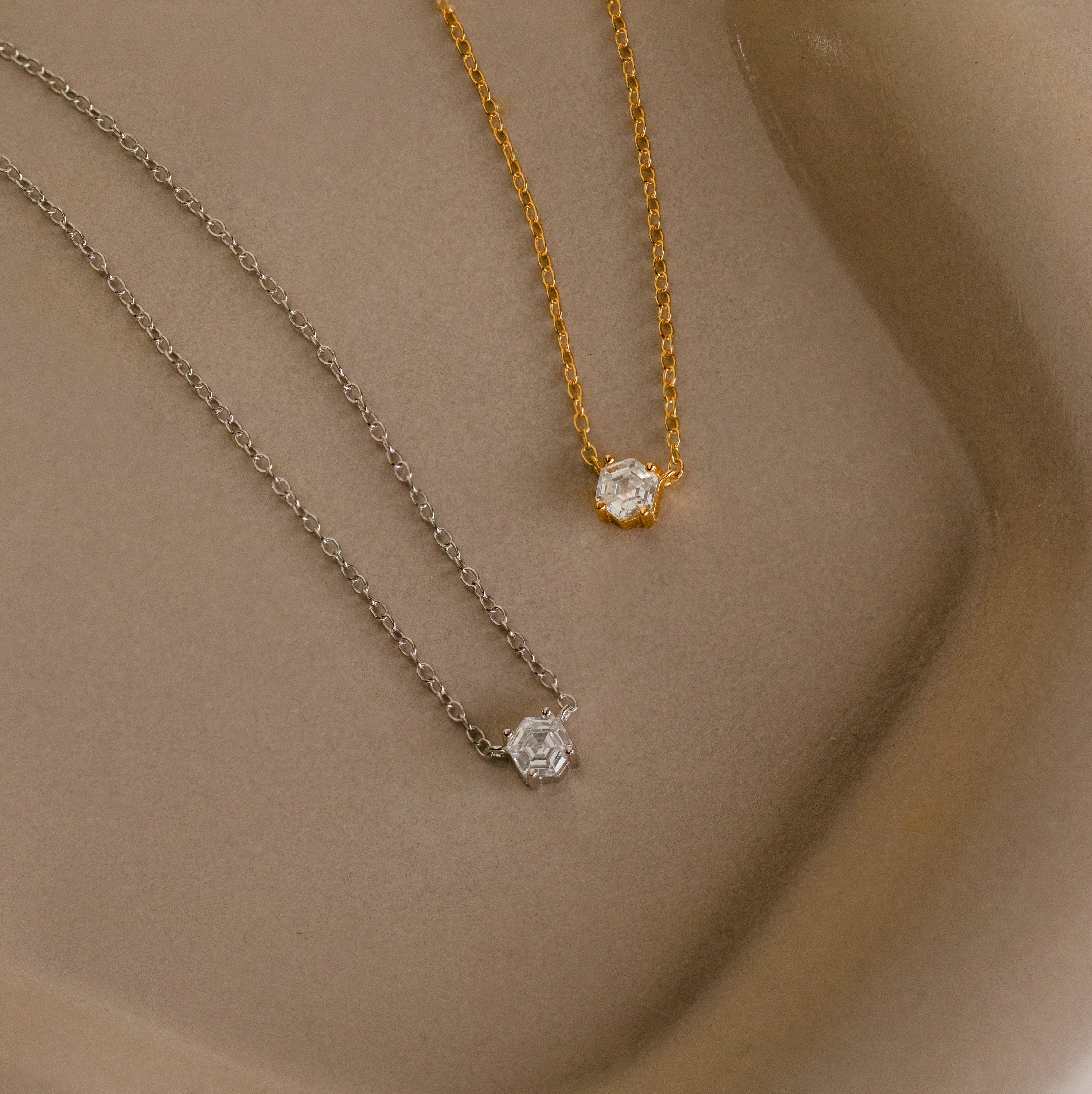 Two delicate Hexagon Diamond Necklaces, one gold and one silver, each featuring a small rose-cut diamond pendant, are displayed on a neutral background.
