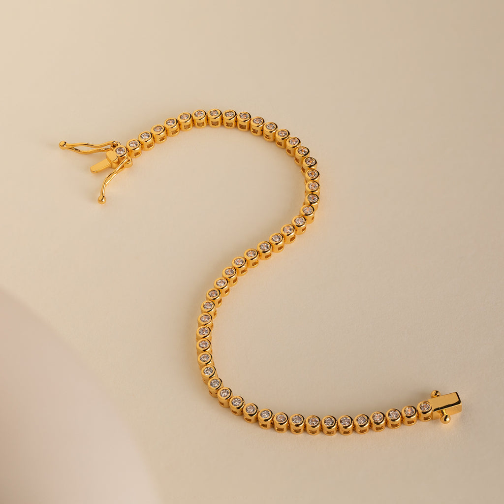 Diamond Bezel Tennis Bracelet featuring round white stones set in a graceful S shape on a beige background—an elegant, minimalist gemstone bracelet and an ideal personalized bridal gift.