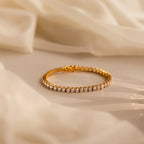 The Bold Diamond Tennis Bracelet, featuring sparkling diamonds, rests on soft beige fabric in gentle natural light—a stylish choice for bridesmaid jewelry or any special occasion.