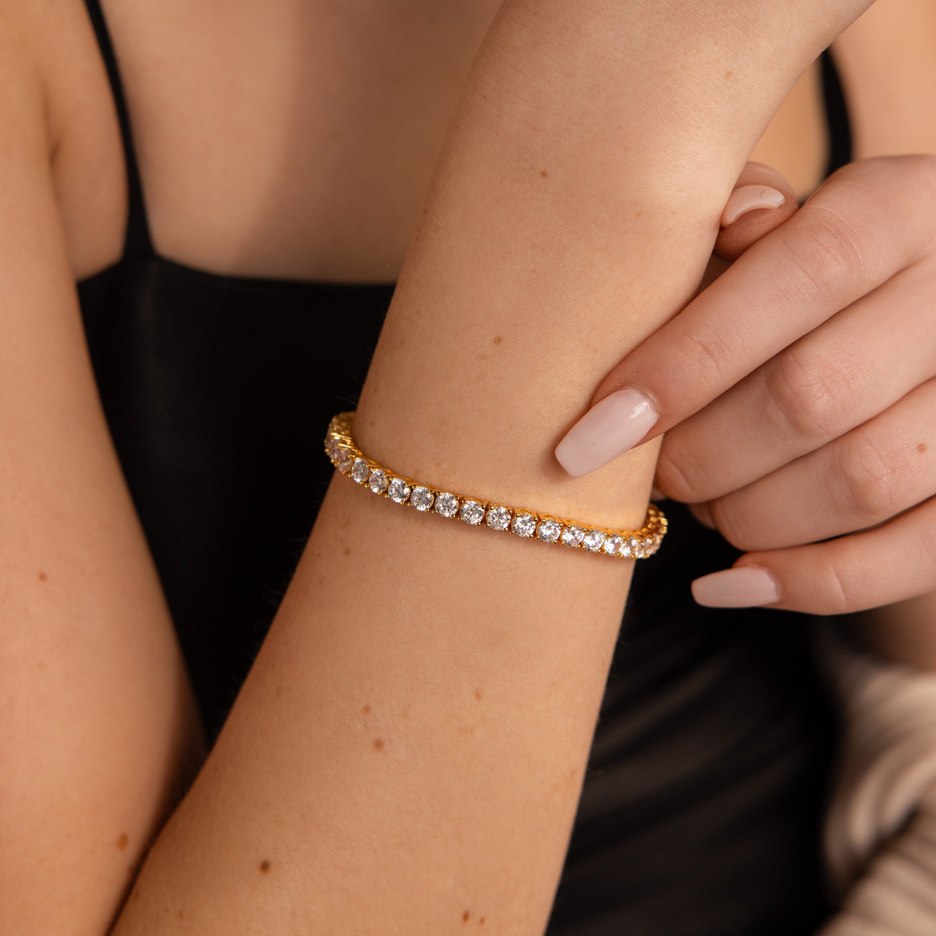 A person wearing the Bold Diamond Tennis Bracelet and a black spaghetti strap top, making it perfect chic jewelry for bridesmaids.