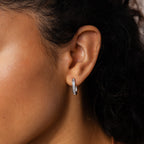 Close-up of a woman's ear adorned with Baguette Link Hoops—minimalist geometric hoop earrings featuring small silver hoops set with sparkling stones.