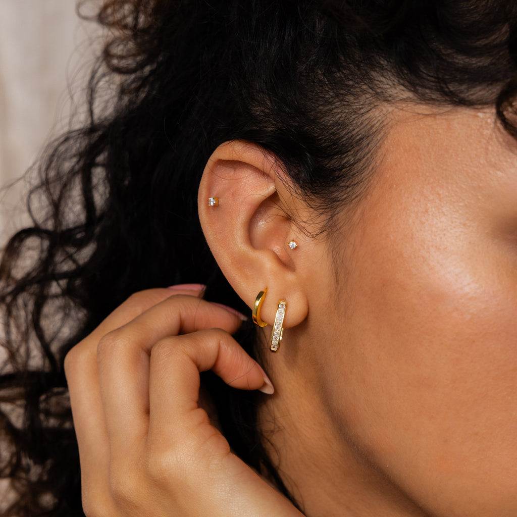 A close-up of a woman's ear adorned with minimalist earrings, featuring the elegant Baguette Link Hoops.