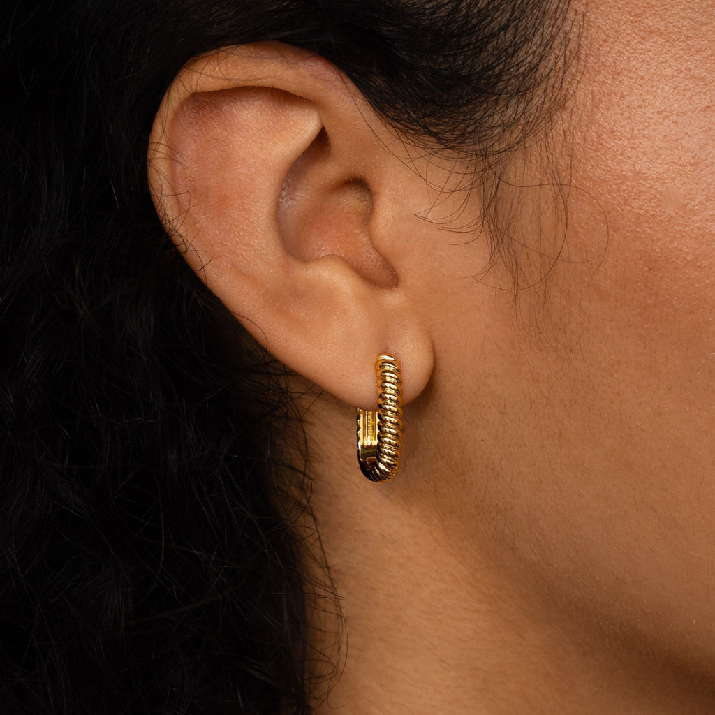 A close-up of a woman's ear adorned with trendy Twisted Link Hoops.
