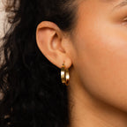Close-up of a woman's ear with curly hair, showcasing the Bold Earrings Stack Set—a chic way to style bold hoops.