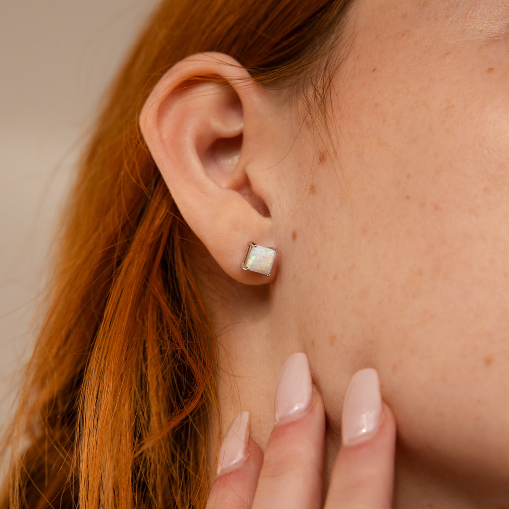 A close-up of a woman's ear adorned with Princess Cut Opal Studs.