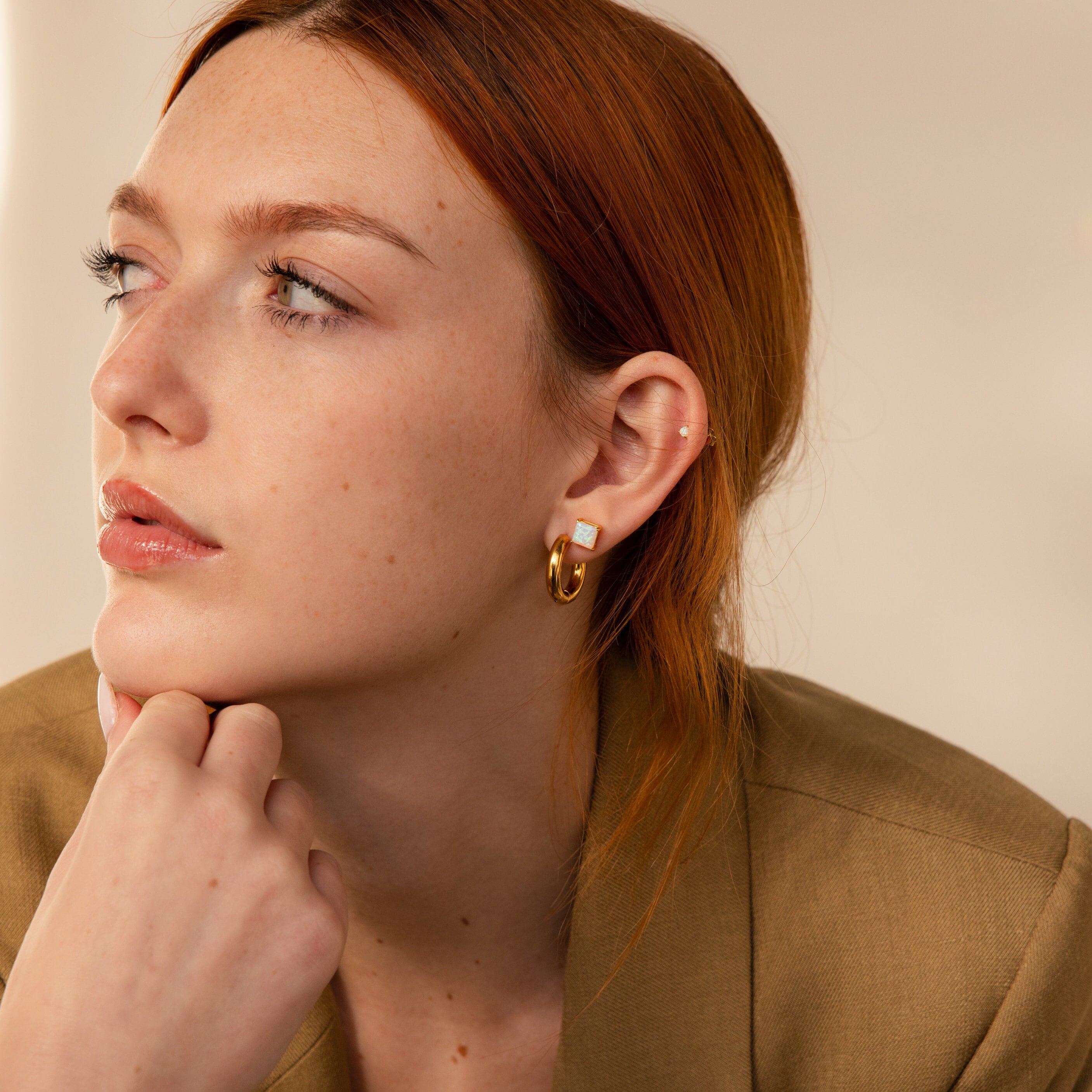 A woman with her hand on her chin elegantly showcases Princess Cut Opal Studs.
