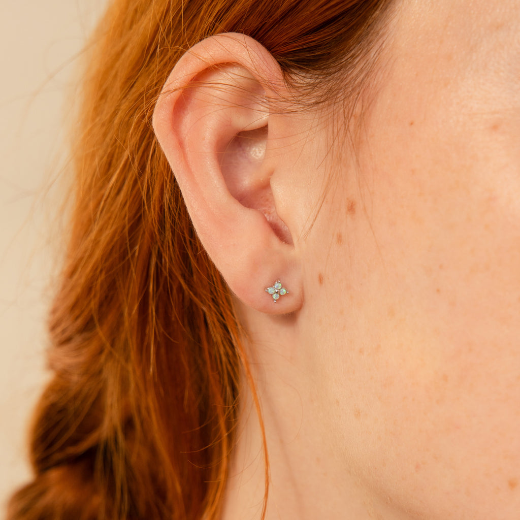 Close-up of a woman's ear adorned with Opal Ivy Flower Studs—delicate opal earrings with a floral design, her red hair visible—making them a perfect meaningful gift.