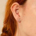 Close-up of a woman's ear adorned with Opal Ivy Flower Studs—delicate opal earrings with a floral design, her red hair visible—making them a perfect meaningful gift.
