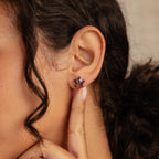 Close-up of model wearing a purple star-shaped earring in gold. 