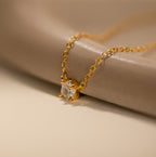 Hexagon Diamond Necklace featuring a rose-cut diamond pendant showcased on a smooth, beige surface.