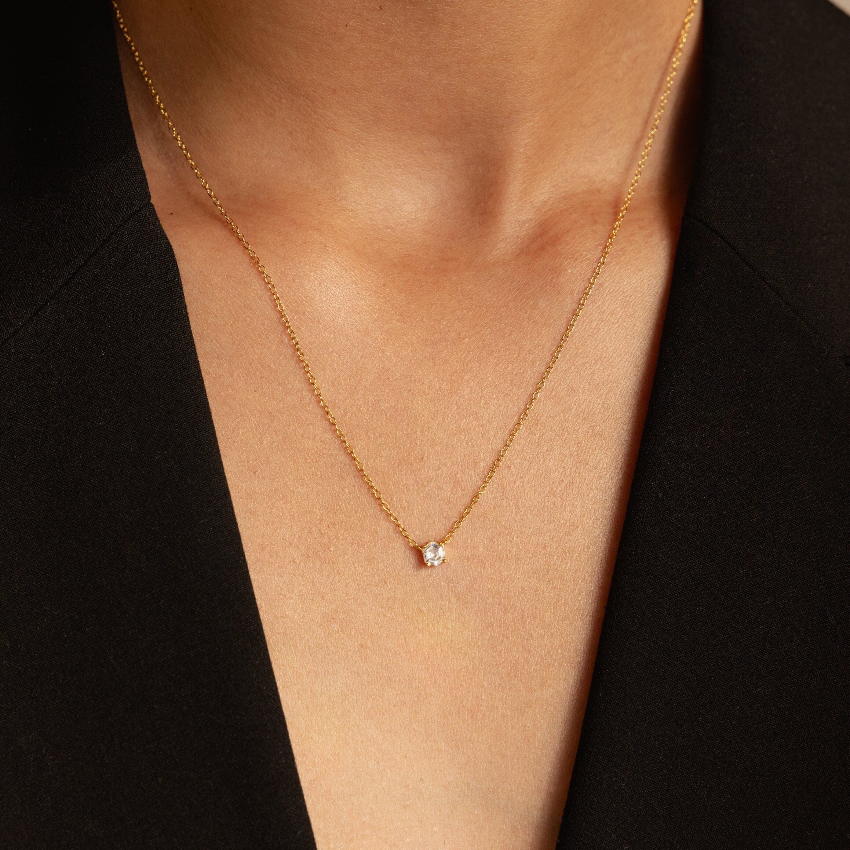 A close-up of the Hexagon Diamond Necklace, featuring a rose-cut diamond pendant, worn with a black V-neck top.