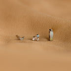 The Opal Inlay Earrings Set features three small earrings with gem settings, beautifully displayed on a textured light brown fabric—an eye-catching opal jewelry set and the perfect gift for her.