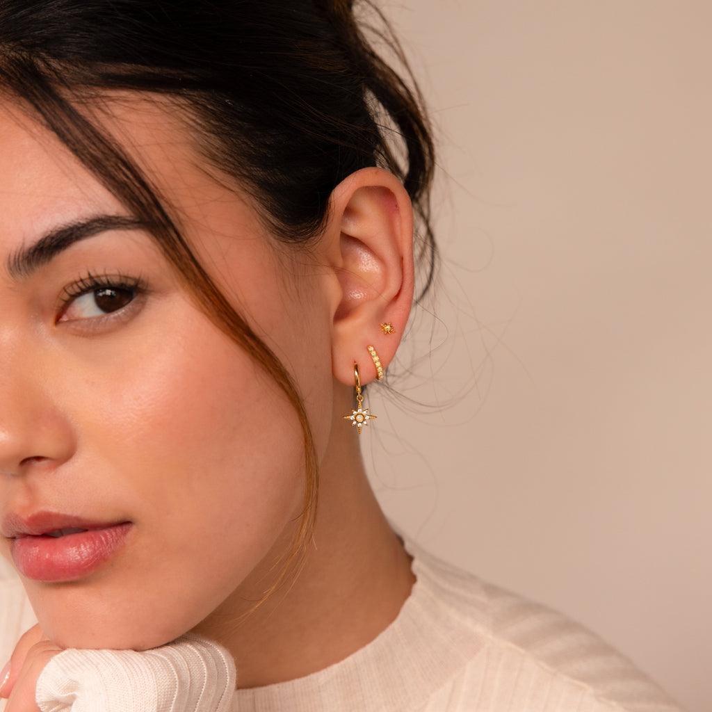 A woman with brown hair wears the Opal Starburst Earrings Set, looking at the camera with a neutral expression.