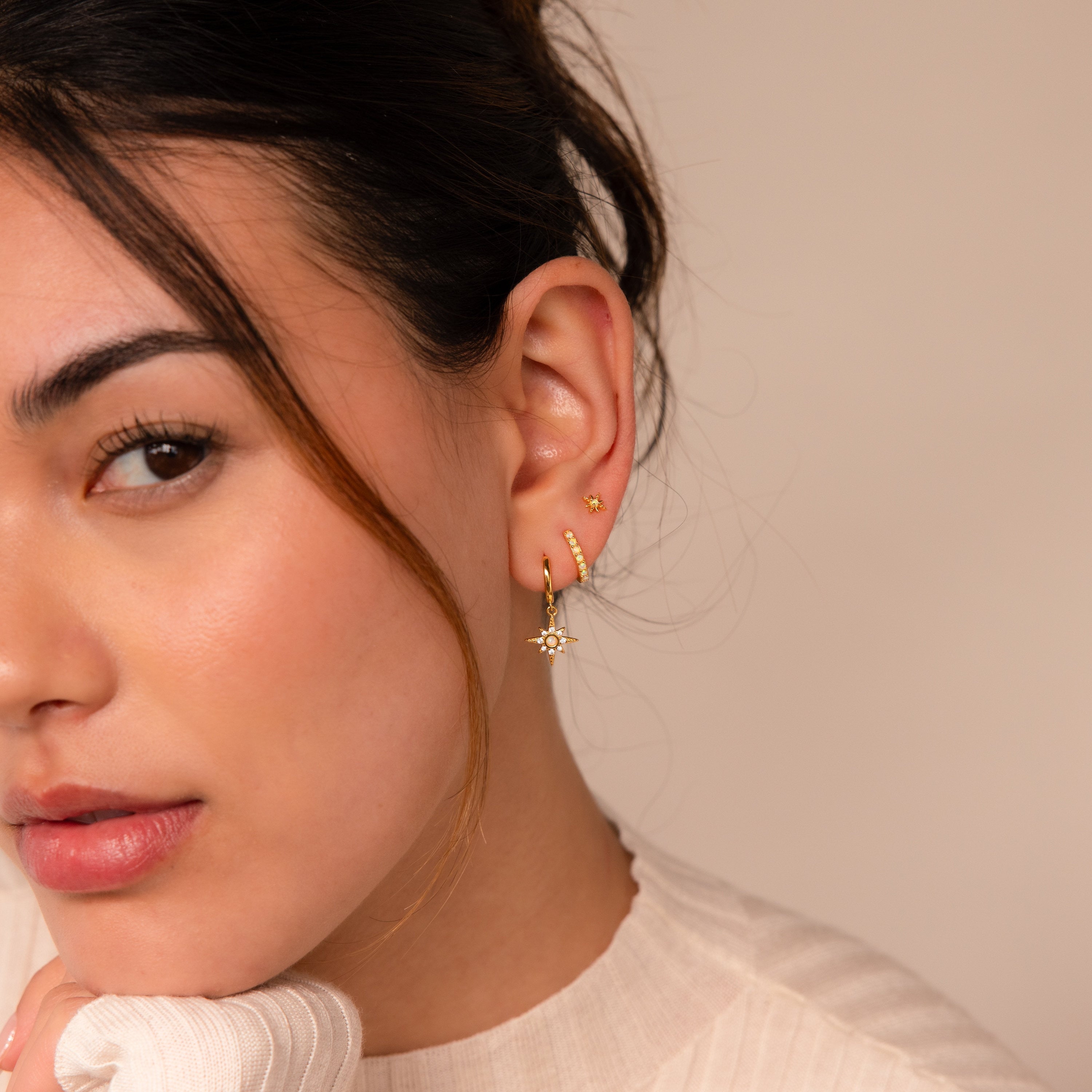 A woman with brown hair wears the Opal Starburst Earrings Set, looking at the camera with a neutral expression.