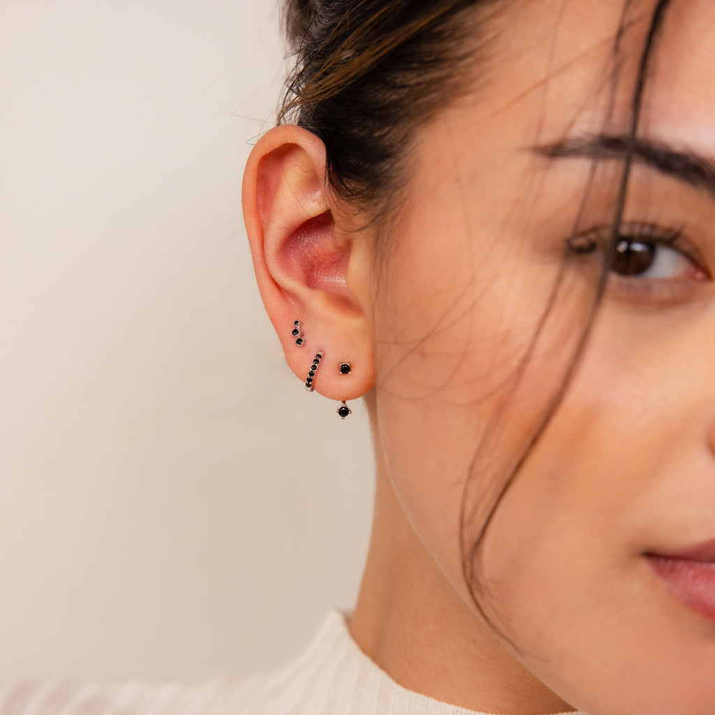 A close-up of a woman's ear adorned with a Black Diamond Earrings Set featuring delicate climber studs.