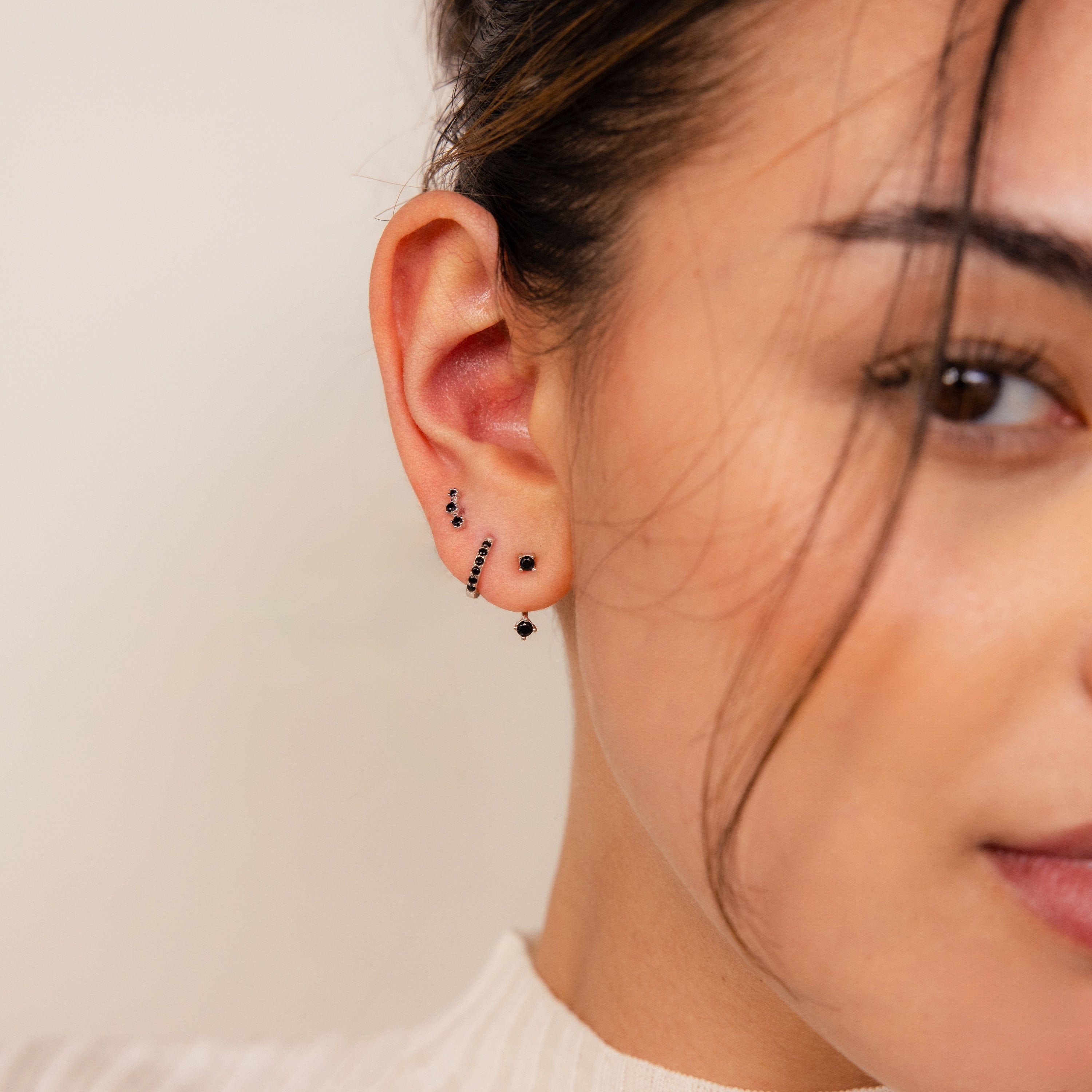 A close-up of a woman's ear adorned with a Black Diamond Earrings Set featuring delicate climber studs.