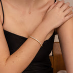 A woman in a black dress wears the Bold Diamond Tennis Bracelet on her arm, her hand resting elegantly on her shoulder—an ideal choice for bridesmaid jewelry.