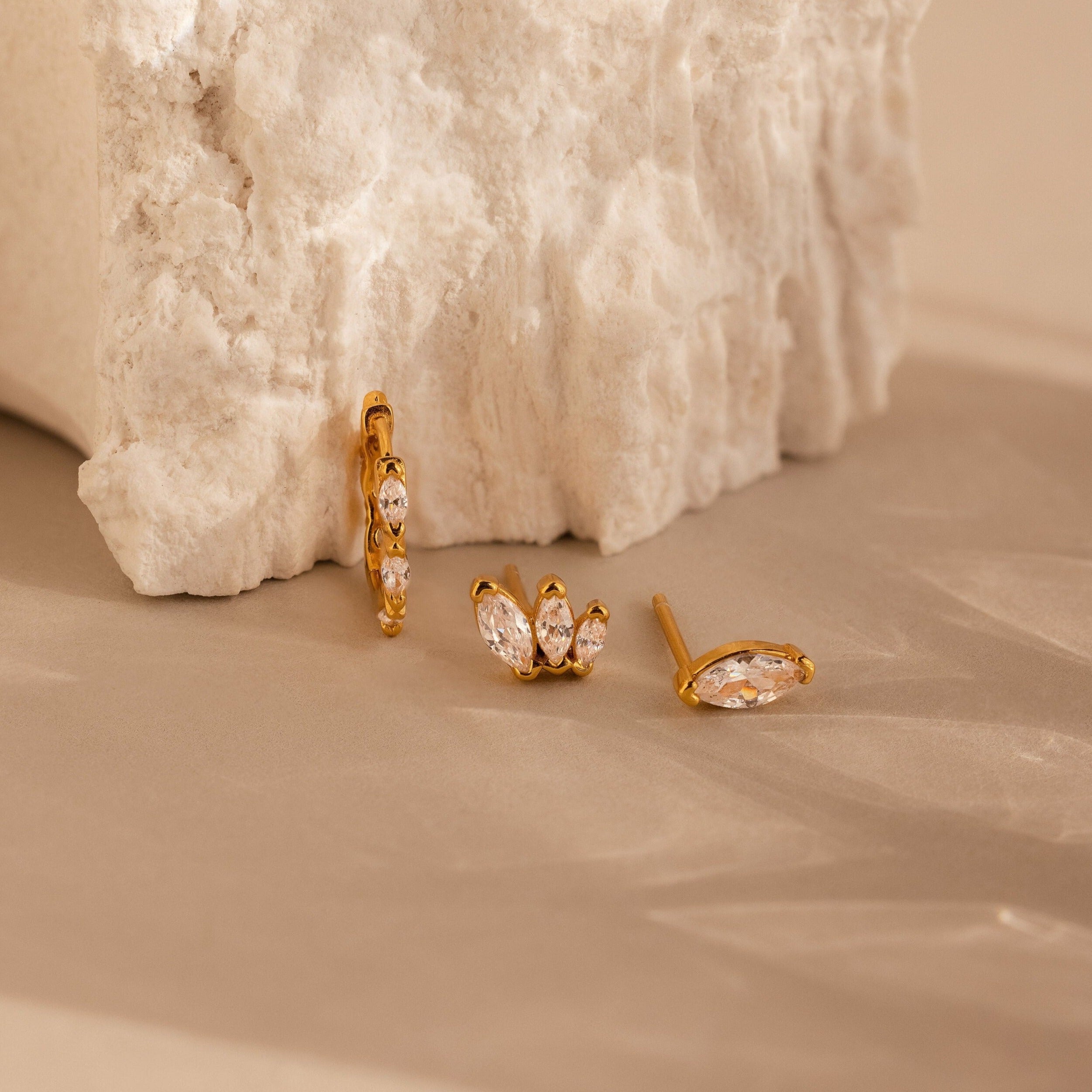 The Marquise Diamond Earrings Set is displayed on a light beige surface with a textured white stone backdrop—perfect as a bridesmaid gift or to add elegant sparkle to any wedding look.