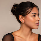 Woman with dark hair in a bun wears the Flower Flat Back Studs Set—small, colorful flower earrings—while facing right against a neutral background.