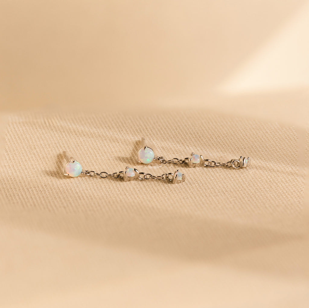 Opal Chain Drop Earrings—delicate silver chains shown on textured beige fabric—make the perfect elegant bridesmaid earrings for special occasions.