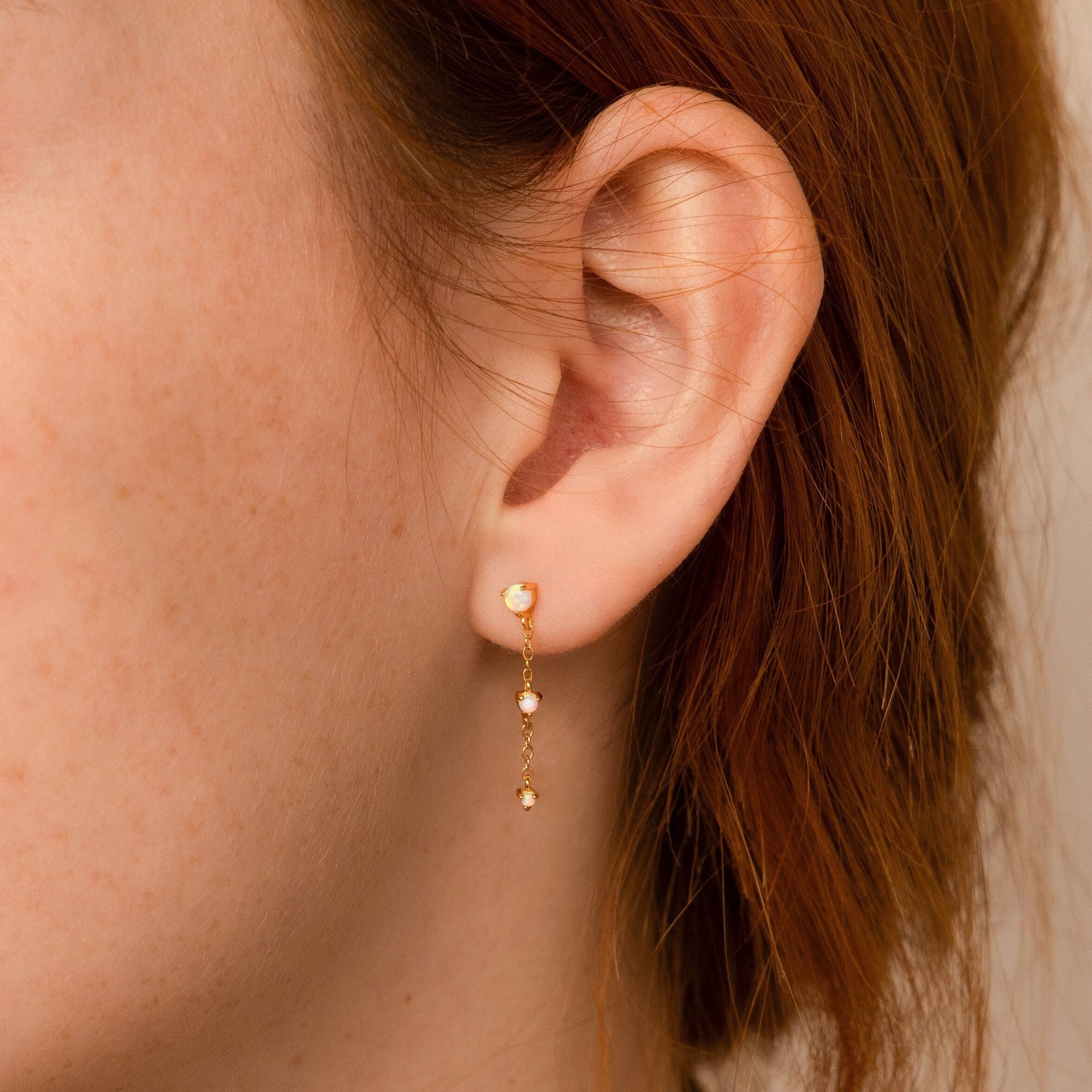 A close-up of an ear wearing the Dainty Opal Stud Earrings Set, a minimalist gold design with small opal accents—perfect for lovers of subtle jewelry.